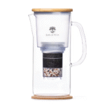 A side view of the ENYA water filter pitcher, showcasing its glass carafe, sustainable bamboo lid, and internal filter cartridge.