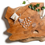 A hand holds the Lotus Vita Crystal Holder, a clear compartment filled with rose quartz, amethyst, and rock crystal gemstones for the ENYA water filter pitcher.